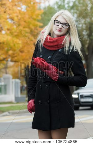 Caucasian student girl with red fully collapsible umbrella in hands and cat eye glasses posing on au