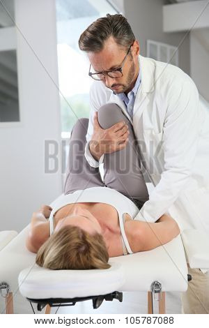 Physiotherapist stretching woman's leg