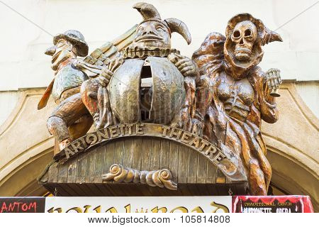 Wooden Sign With Carved Wooden Figures Of A Man, The Jester And Death