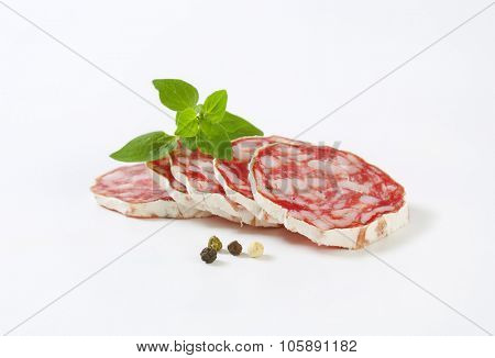 close up of thin slices of french dry salami on white background