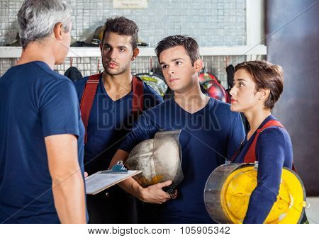 Mature fireman discussing plan with team at fire station