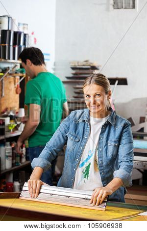 Portrait of confident mid adult woman silkscreening in studio