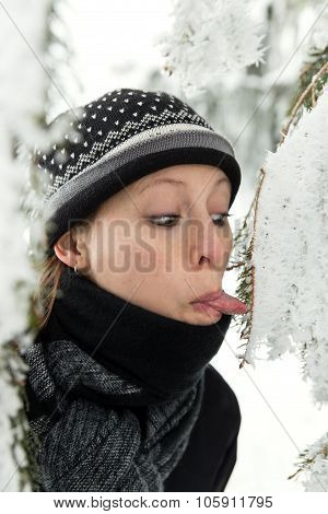 Woman Protuding Her Tongue To The Icy Fir Needles