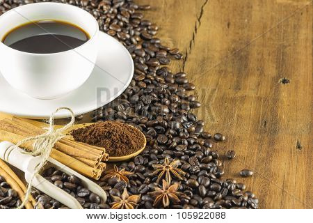 Coffee On The Cup With Coffee Beans And Cinnamon Sticks On Wood Background, Warm Toning, Selective F