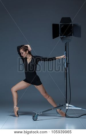 The beautiful ballerina posing on dack blue background