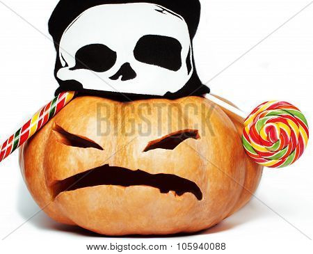 halloween holiday traditional scary smiling orange pumpkin in black skull hat and candys isolated on