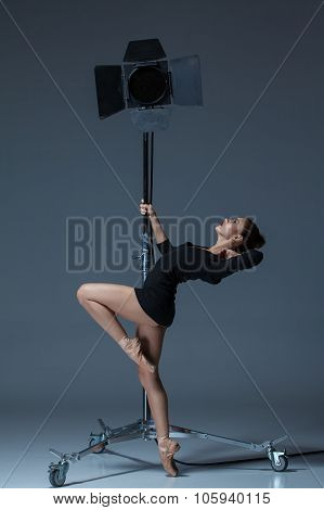 The beautiful ballerina posing on dack blue background