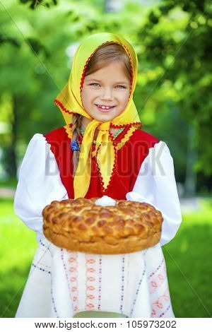 Little girl is dressed in the Russian national dress. She holds in his hands the fresh loaf. It is a custom to meet the guests.