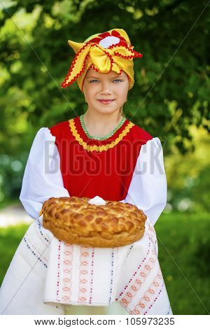 Little girl is dressed in the Russian national dress. She holds in his hands the fresh loaf. It is a custom to meet the guests.