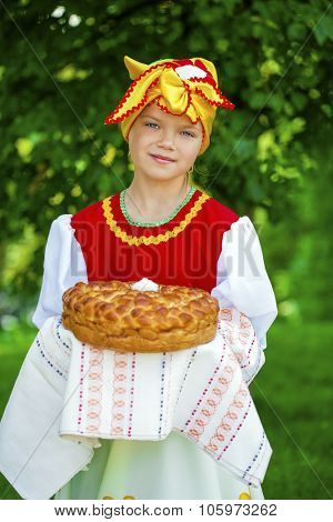 Little girl is dressed in the Russian national dress. She holds in his hands the fresh loaf. It is a custom to meet the guests.