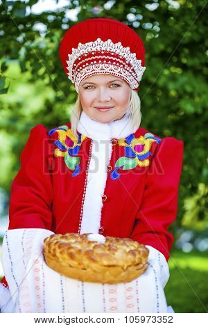 Young woman is dressed in the Russian national dress. She holds in his hands the fresh loaf. It is a custom to meet the guests.
