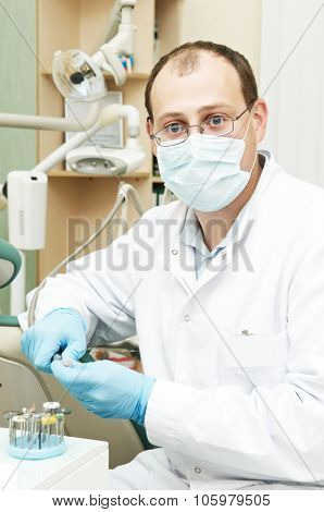 Portrait of male dentist with mask and gloves on his working place in dental clinic