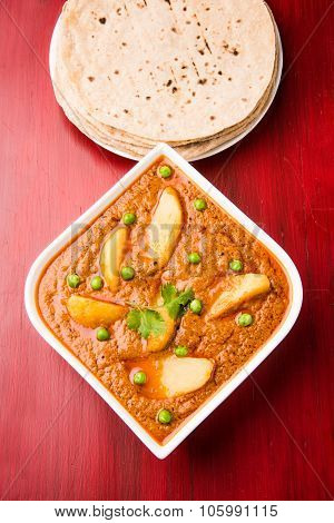 potato curry or aalu masala or aaloo masala with green peas, served with indian bread / roti / chapa