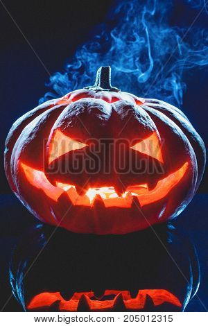 Halloween pumpkin ghost lantern with smoke on dark background