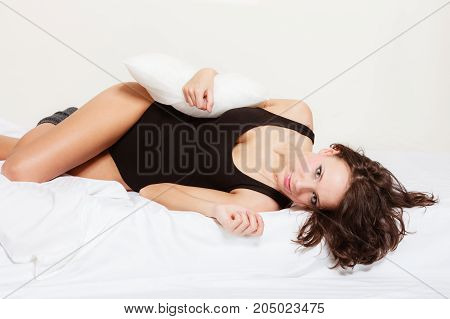 Sexy lazy girl in black body lying with pillow on the bed. Young attractive woman relaxing lazing in bedroom at morning.