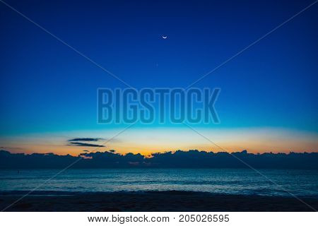 cresent moon at first light over the ocean