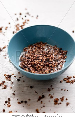 Healthy cereal breakfast. Sweet granola with milk in teal bowl on wooden background. Wholegrain vegetarian morning tasty food.