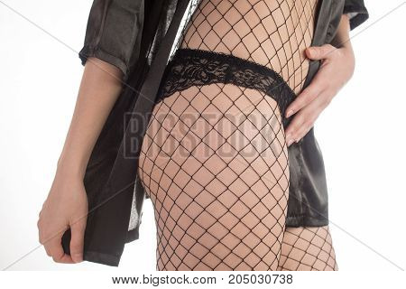 Sexy slender girl with beautiful legs in pantyhose mesh and black lacy panties over white background
