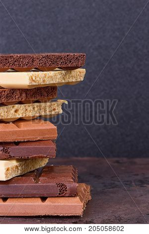 stack of different kind porous chocolate pieces on a dark background.