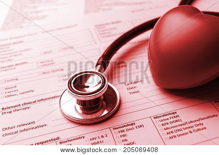 stethoscope red heart and medical information form on desk heart healthcare technology medical research diagnosis medical report record and history patient concept selective focus red color tone