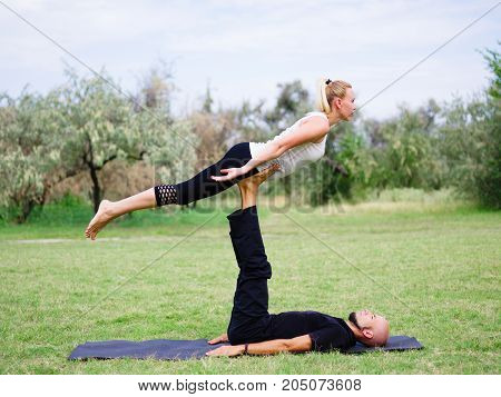 Beautiful woman and girl practise yoga pose outside. Women doing stretching workout in park outdoors at sunset.