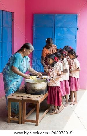 PONDICHERY PUDUCHERY INDIA - SEPTEMBER 04 2017. Unidentified boys girls children get in lines with their plates to be served of rice and eggs at the outdoor canteen of the school.