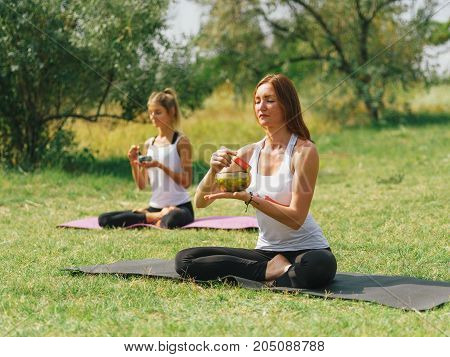 People at the health club outside with personal trainer, learning the correct form.