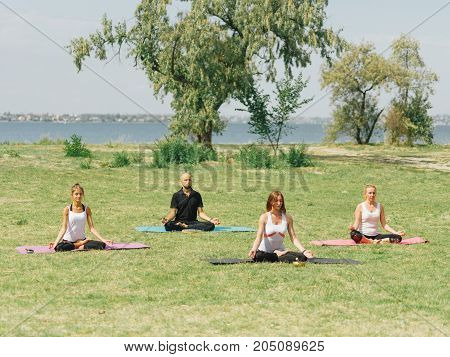 People at the health club outside with personal trainer, learning the correct form.