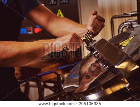 Brewer working in a brewhouse. Hands and kettle close-up