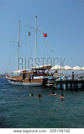 Marmaris, Turkey - August 16, 2017: Family swim near jetty and docked boat during summer holiday in Marmaris, Turkey