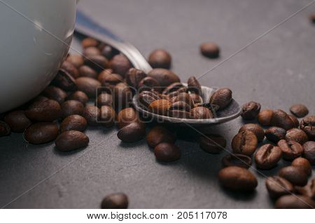 Coffe beans on a spoon on gray rock background