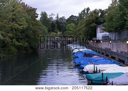 small boats in canal with tree and water reflection for fishing and sailing with raincovers at evening