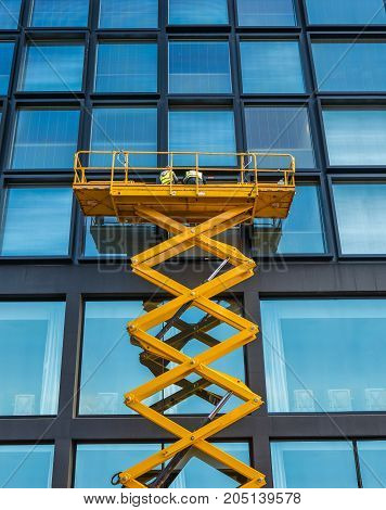 Workers On A Scissor Lift Cleaning Windows On A Financial Building Downtown