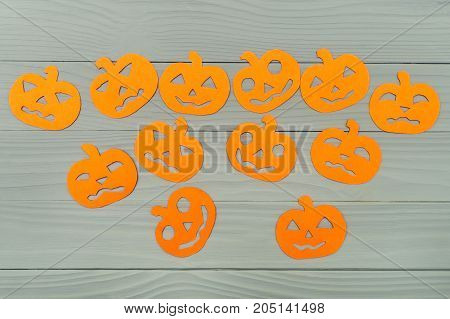 Many different halloween pumpkin paper silhouettes on a gray wooden board. Halloween celebration