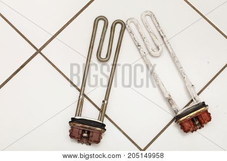 Mechanical technology industry concept. Comparision of two heaters. New washing machine part and old covered in sediment.