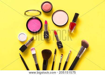 Cosmetics and fashion background with make up artist objects: lipstick eye shadows mascara eyeliner concealer nail polish yellow colorful background. Lifestyle Concept