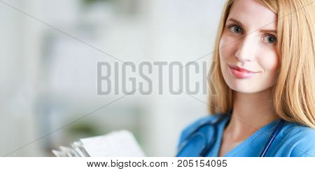 Happy doctor woman is standing in the near window