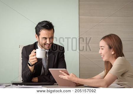 beautiful young asian business woman and caucasian man look at tablet for business project