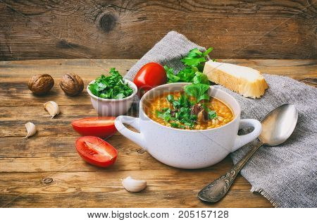 kharcho soup in white bowl from rice beef tomatoes spicy herbs walnuts bread canvas towel on an old wooden table traditional Georgian cuisine