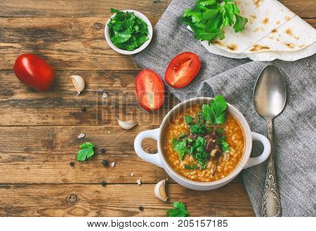 kharcho soup rice beef tomatoes herbs in white bowl pita bread on an old wooden table traditional Georgian cuisine top view
