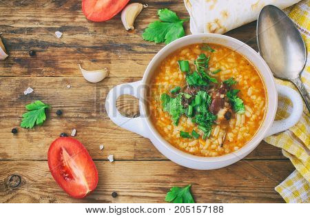 kharcho soup rice beef tomatoes herbs in white bowl pita bread on an old wooden table traditional Georgian cuisine top view closeup