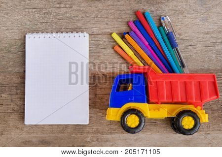 Open white notepad with colorful felt-tip pens and ball pens on the wooden table. Space for text