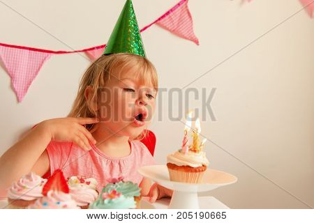 happy cute little girl make wish blow candles at birthday party