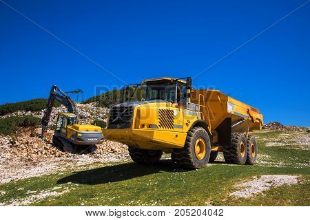 VOGEL MOUNTAIN SLOVENIA - AUGUST 30 2017: Construction machinery for crushing stone Volvo bulldozer and large truck dumper working on mountain