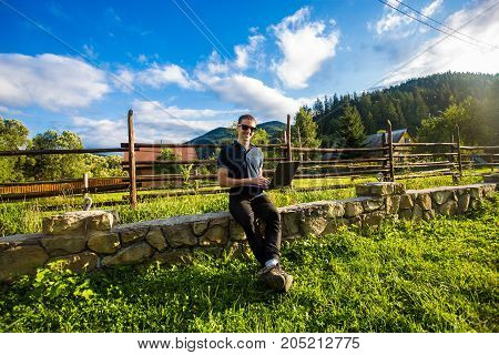 Young man works at laptop outdoor in the mountains at sunset
