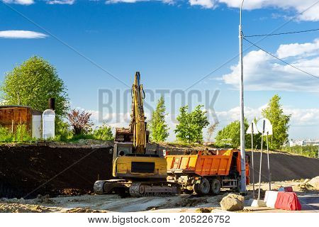 Crawler Excavator loads truck with rubble using bucket. Construction of high-speed bypass road around Krasnoe Selo Saint Petersburg. Heavy industrial machinery equipment for excavation works. Russia