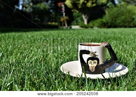 coffee time. coffee grounds on the bottom of the mug. a cup on the grass. green meadow and white tableware. fortune telling, monkey cup, monkey background, funny and cute cup, green background