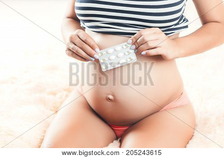 Pregnant Girl In The Hands Holding Pills