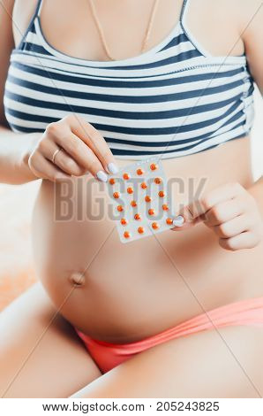 Pregnant Girl In The Hands Holding Pills