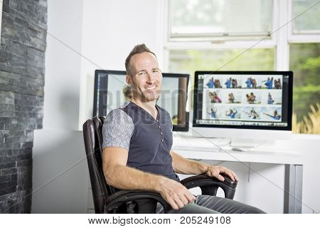 A Handsome photographer with camera at office with computer on the front